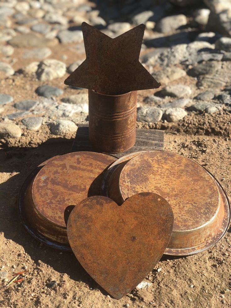 two heart shaped tin cans sitting on the ground next to a star and a metal canister