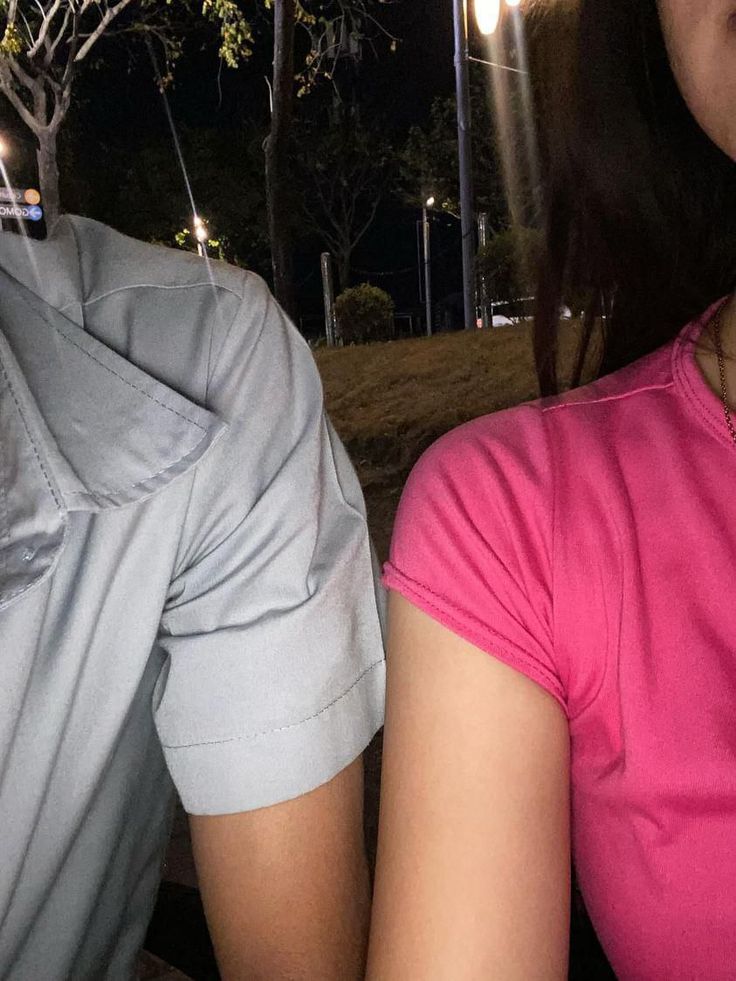 a man and woman sitting next to each other in front of a tree at night