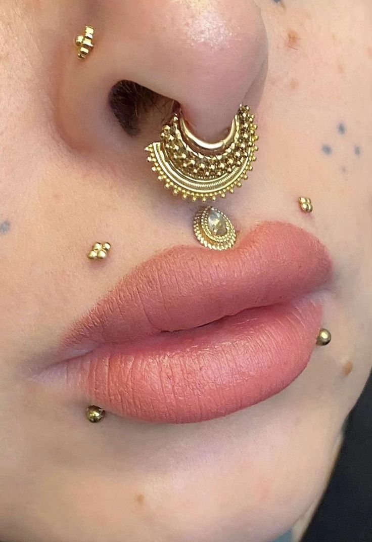 a close up of a person with gold jewelry on their nose and lip piercings