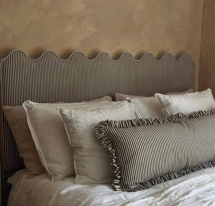 a bed with white and black pillows on top of it next to a wall mounted clock