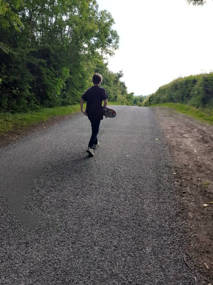 a man is running down the road with a skateboard in his hand while wearing a black shirt