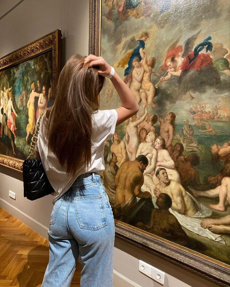 a woman standing in front of a painting looking at it