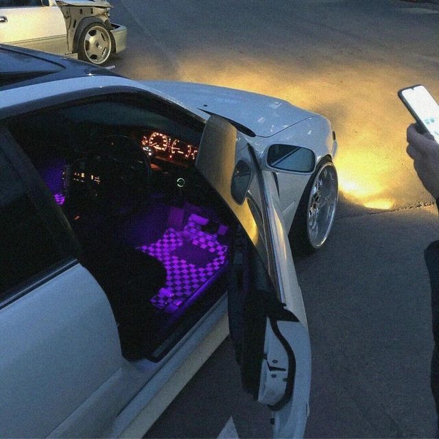 a person holding a cell phone standing next to a car