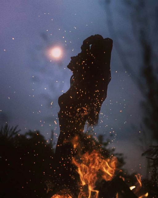 the silhouette of a person standing in front of a fire with lots of sparks coming out of it