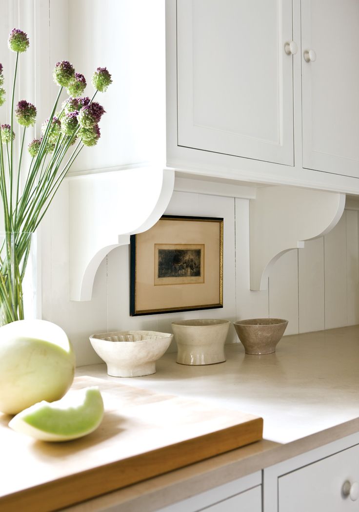 a vase with flowers sitting on top of a counter next to two bowls and a bowl