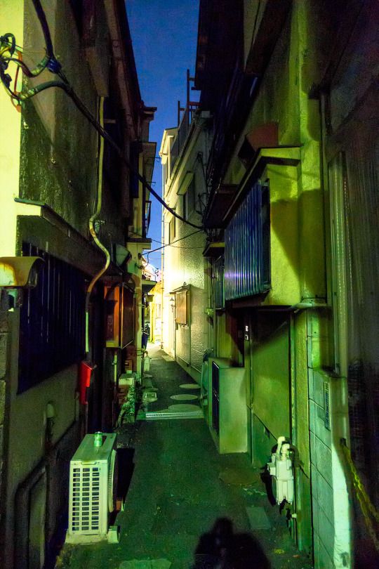 a narrow alleyway in an old city at night with no one on the sidewalk