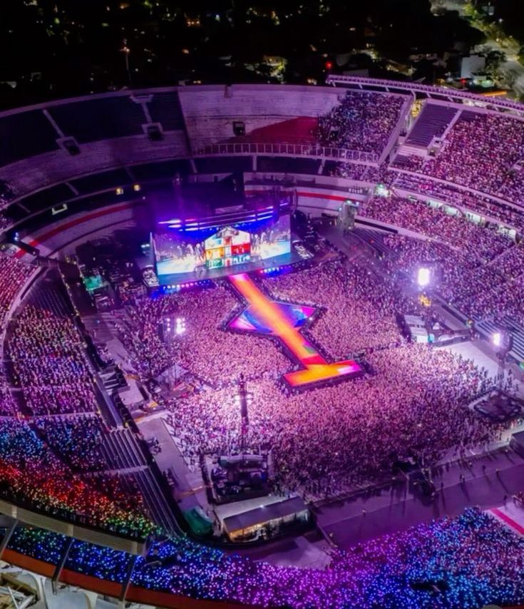 an aerial view of a concert venue at night, with the stage lit up in purple and blue