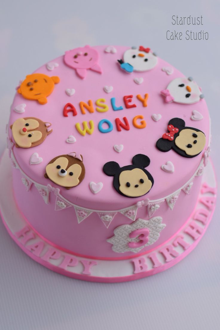 a pink cake with mickey mouse and other characters on it