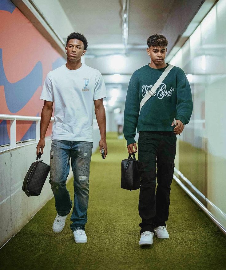 two young men walking down a hallway carrying bags and briefcases in their hands,