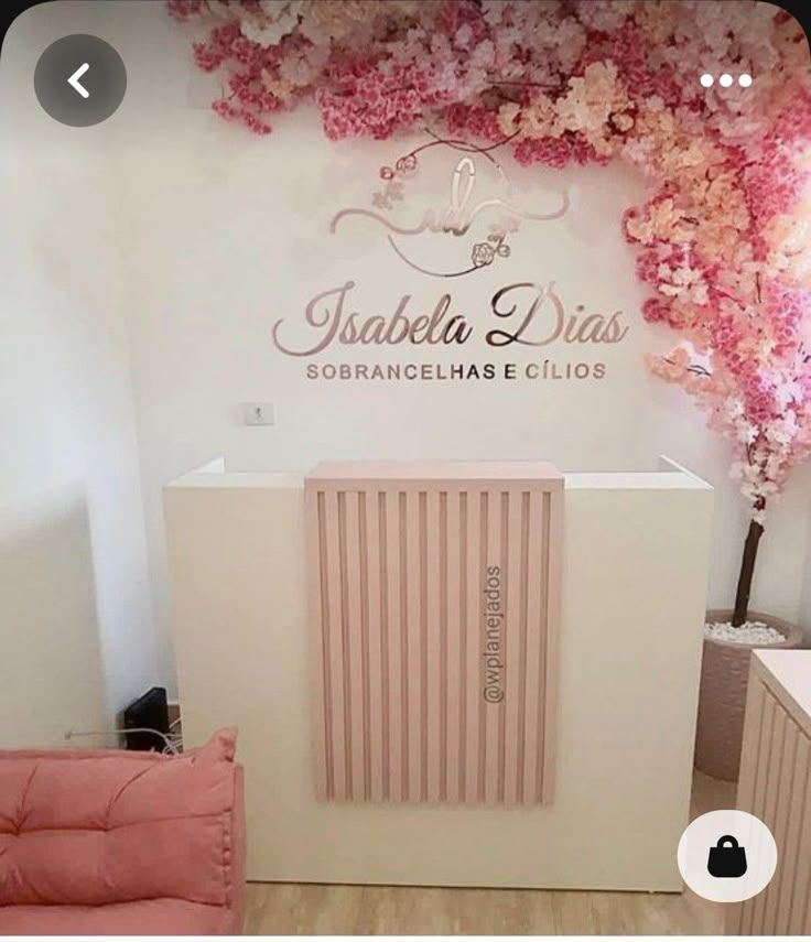 a pink chair sitting in front of a white wall with flowers on it's side