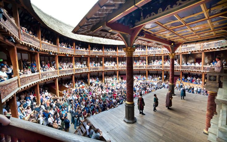 a large group of people standing inside of a building with lots of wooden floors and balconies