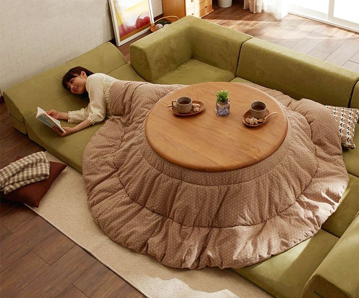 a woman laying on the floor reading a book in front of a round coffee table