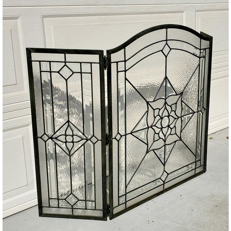 an ornate iron gate with glass panels on the sides and bottom panel, in front of a white garage door