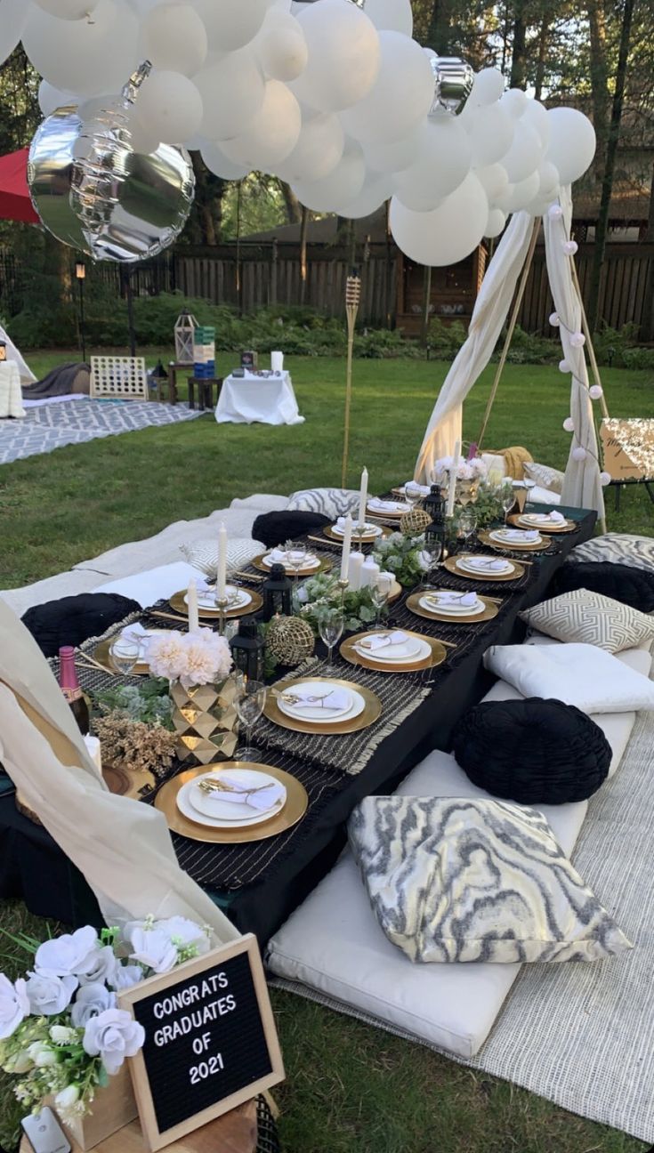 a table set up with balloons, plates and napkins for an outdoor dinner party