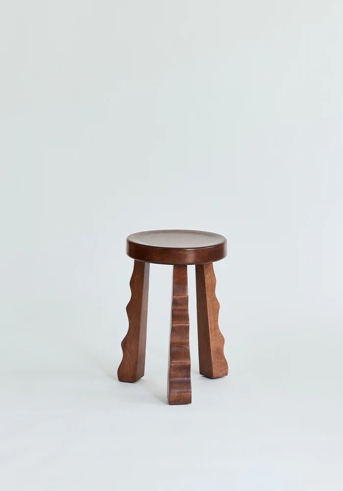 a small wooden stool sitting on top of a white floor