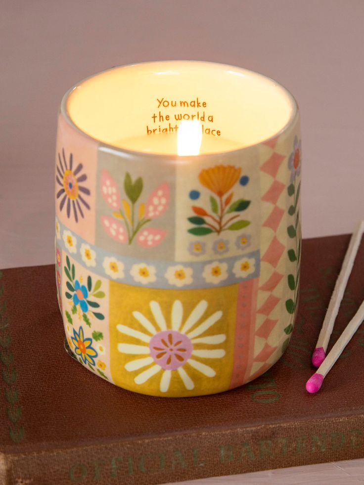 a candle that is sitting on top of a wooden table next to two sticks and a book