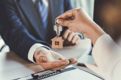 two people sitting at a table with keys in their hands and a house shaped keychain