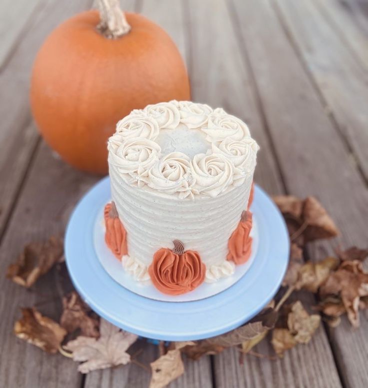 a white and orange cake sitting on top of a blue plate next to a pumpkin