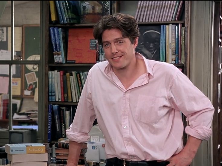 a man standing in front of a bookcase with books on the shelves behind him