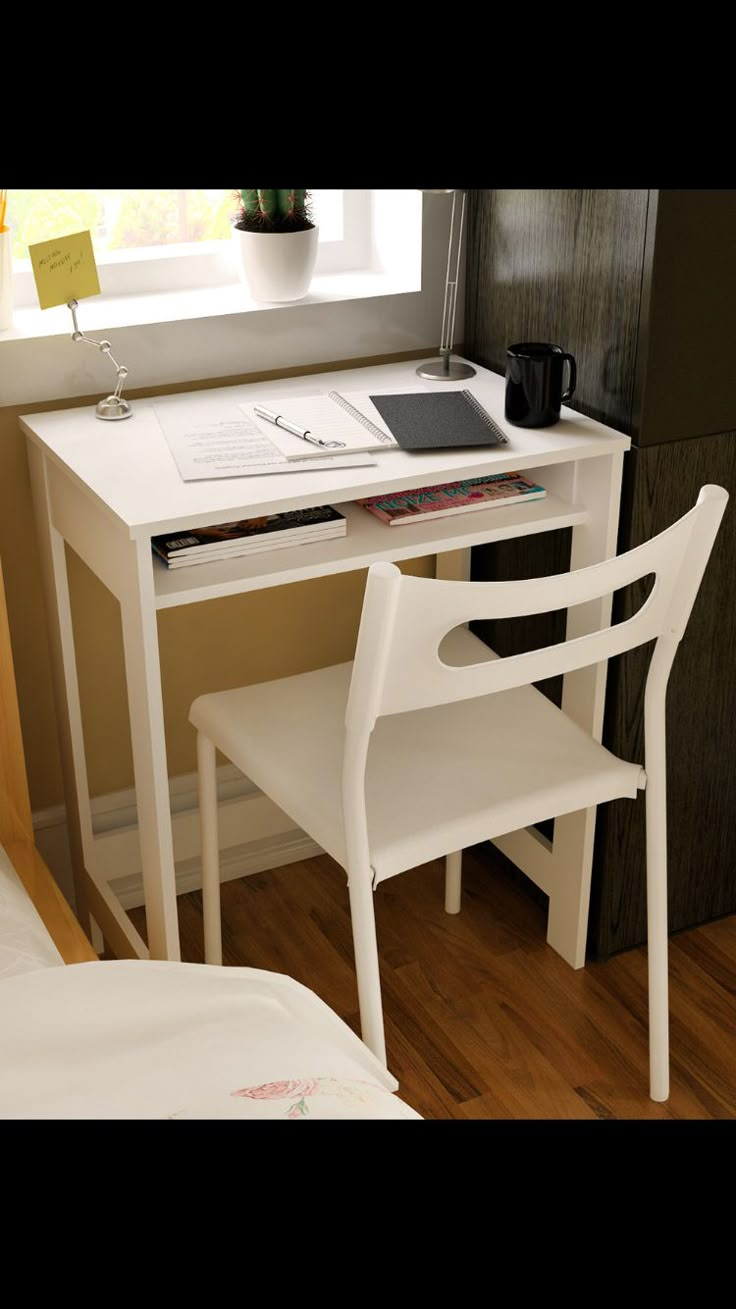 a white desk with a laptop computer on top of it next to a chair and window