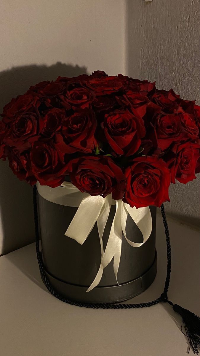 a large bouquet of red roses in a black and white hat box on a table