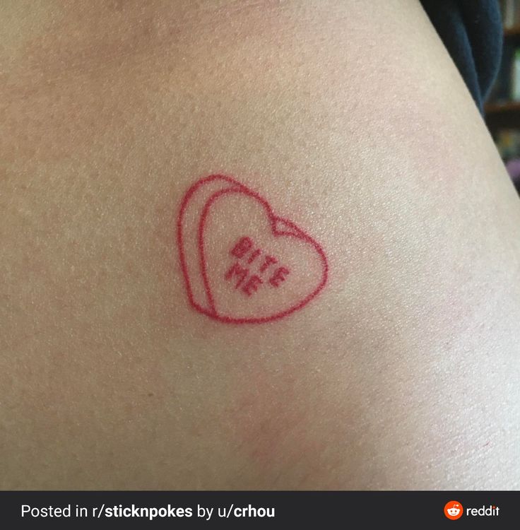 a small heart tattoo on the back of a woman's left arm, which reads i love me