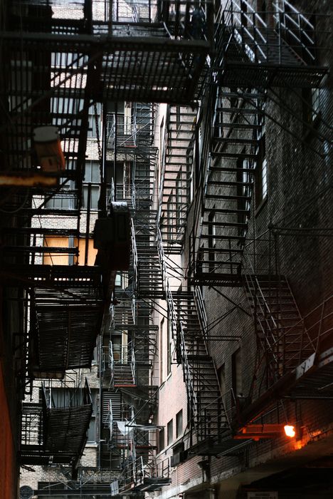 an alleyway with fire escapes and staircases in new york city, ny at night