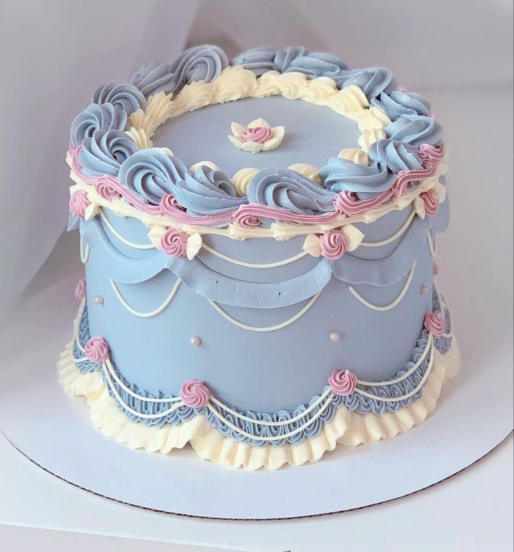 a blue cake with white frosting and pink decorations