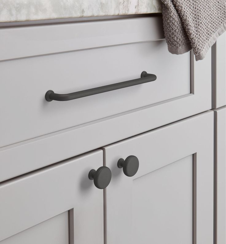 a close up view of the handles on a white kitchen cabinet with gray knobs