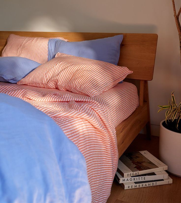 a bed with blue and orange sheets on top of it next to a potted plant