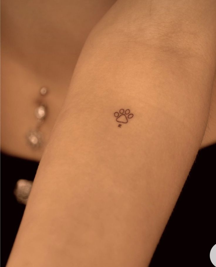 a woman's arm with a small dog paw tattoo on the left side of her arm