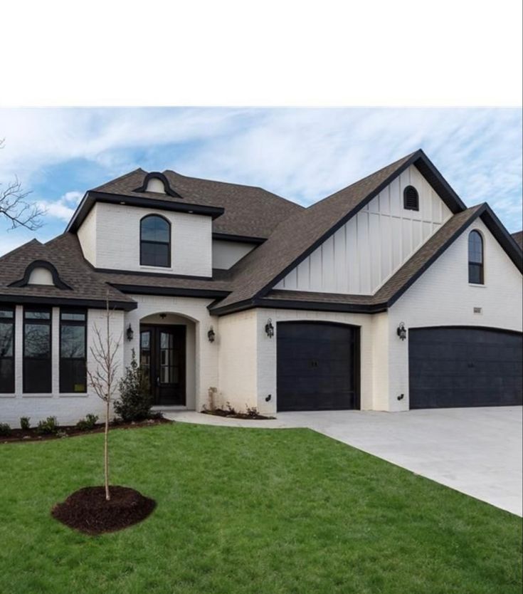 a large white house with black garage doors