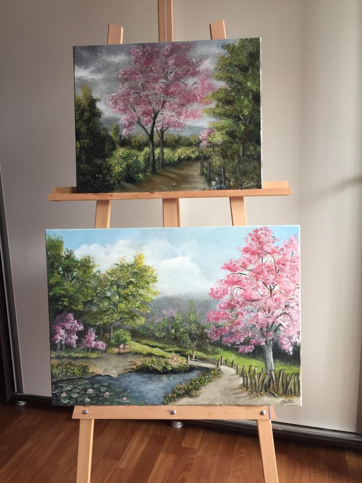 two easels with paintings on them sitting in front of a window, one has pink flowers and the other is green