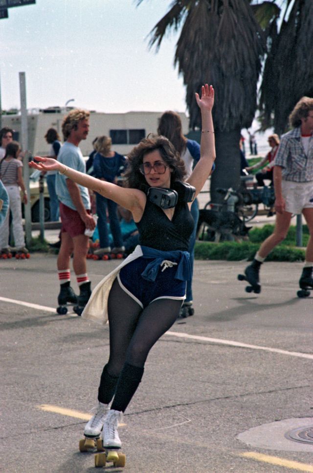 a woman riding a skateboard down a street next to people on rollerblades