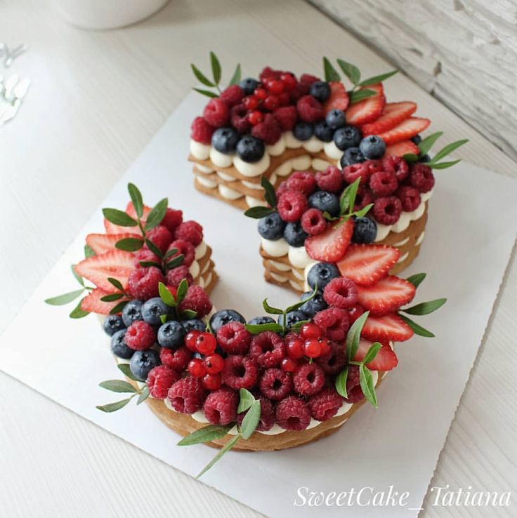 a cake decorated with berries, blueberries and raspberries in the shape of the letter e