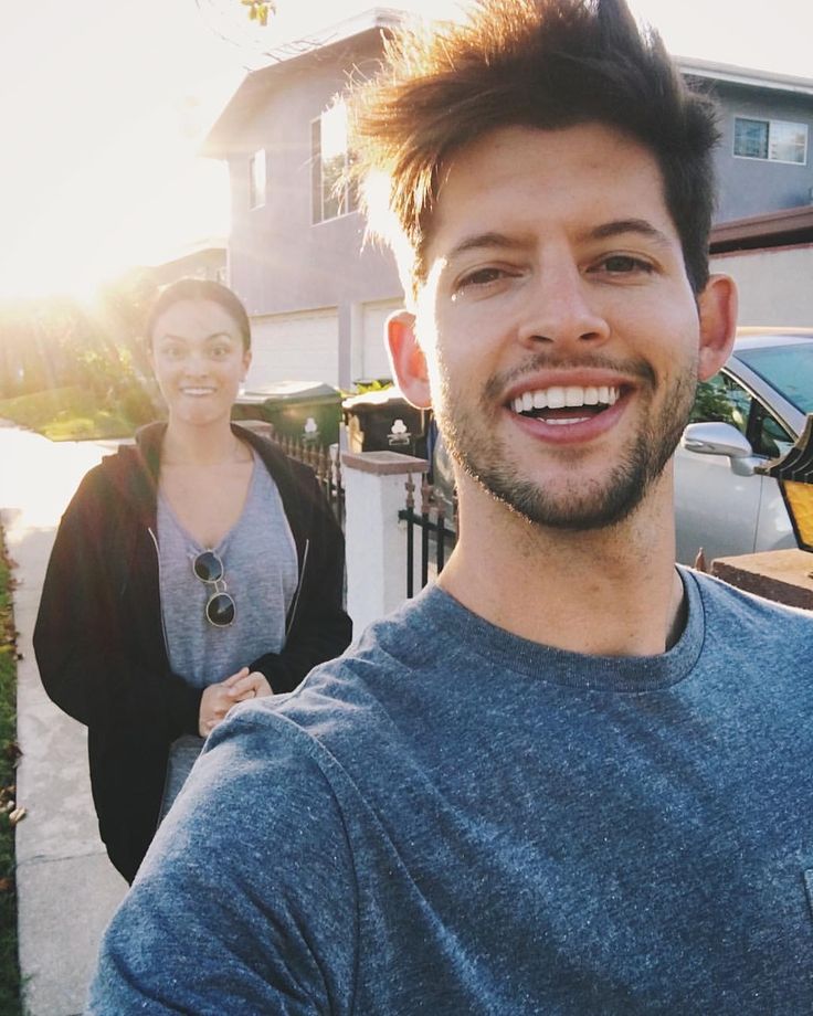 a man standing next to a woman in front of a house with the sun shining on her