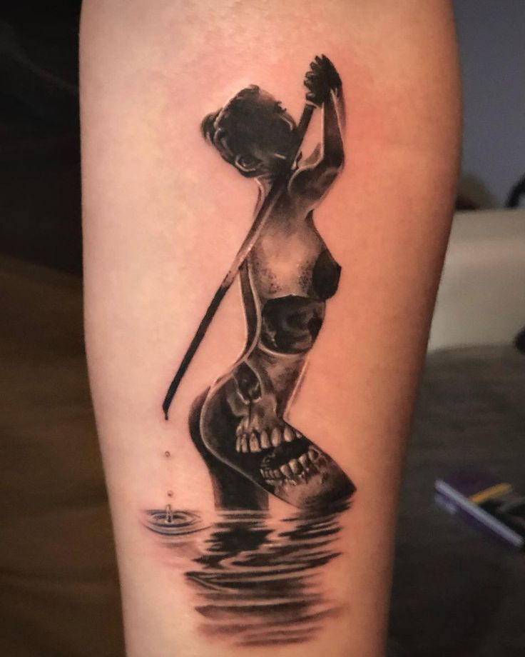 a woman with a knife and skull tattoo on her arm is standing in the water