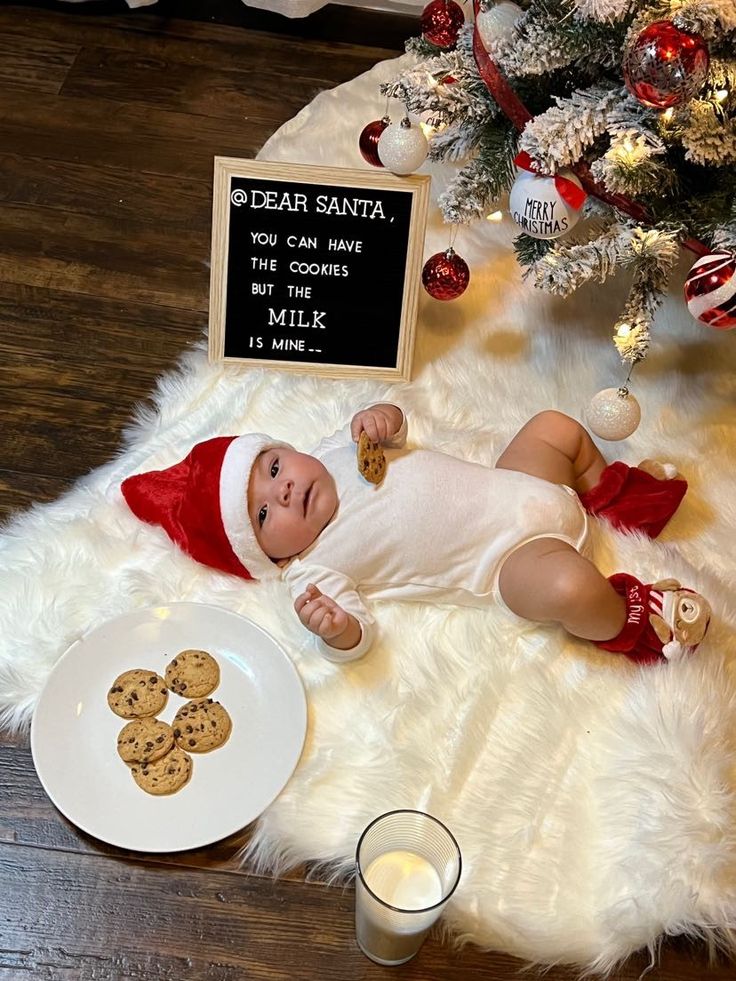 a baby is laying on the floor next to a plate of cookies and a glass of milk