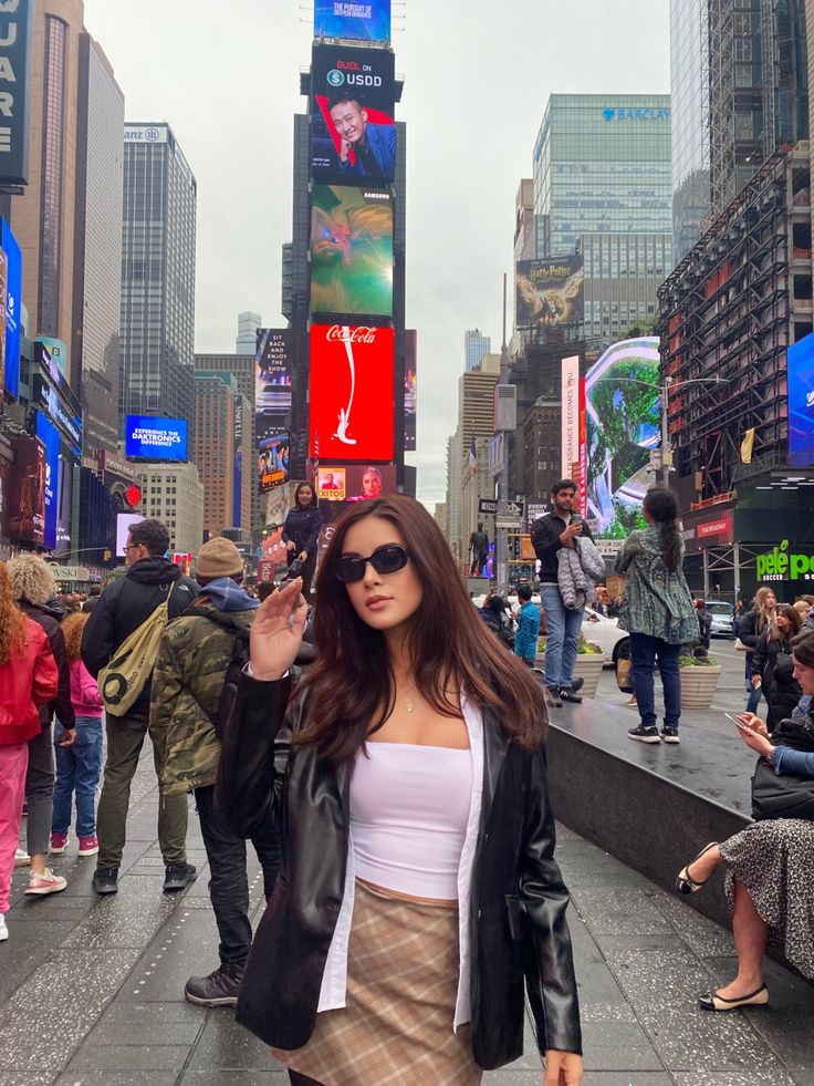 a woman is walking down the street with her hand up to her ear and wearing sunglasses