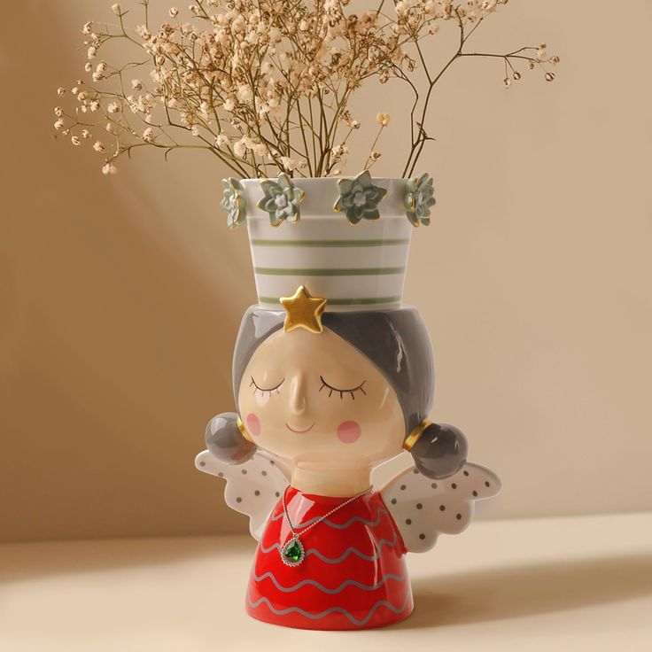 a vase with flowers in it and a little angel figurine next to it