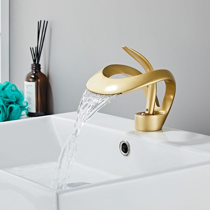 a gold faucet running water from it's spout in a bathroom