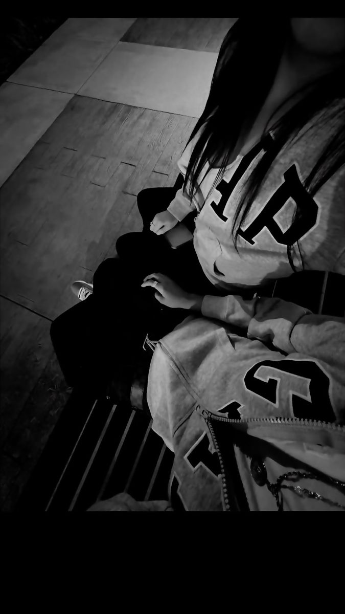 black and white photograph of a woman sitting on a bench with her hands in her pockets