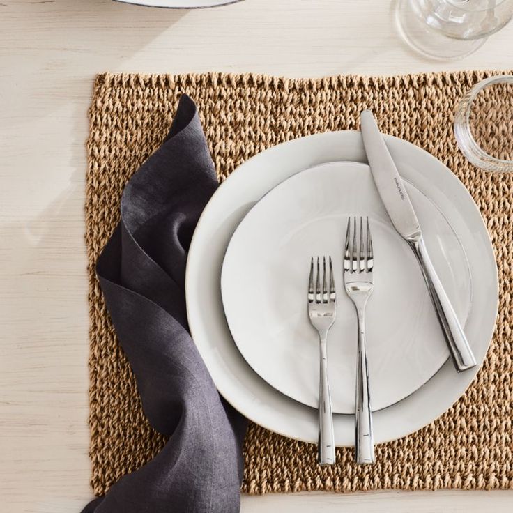 the place setting is ready to be served with silverware and black satin napkins