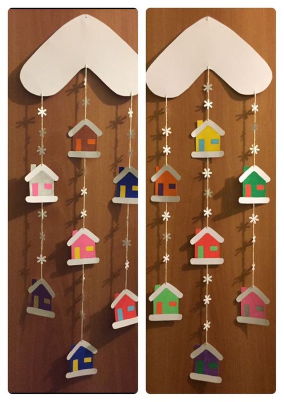 the paper houses are hanging from strings on the wooden wall with stars and snowflakes