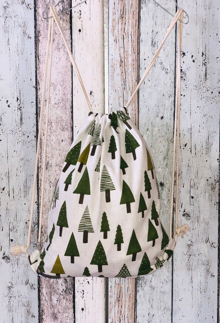 a drawstring bag with trees on it hanging from a wooden wall next to white boards