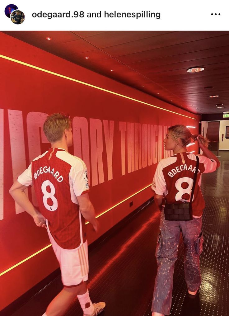 two young men standing in front of a red wall with the number 8 on it