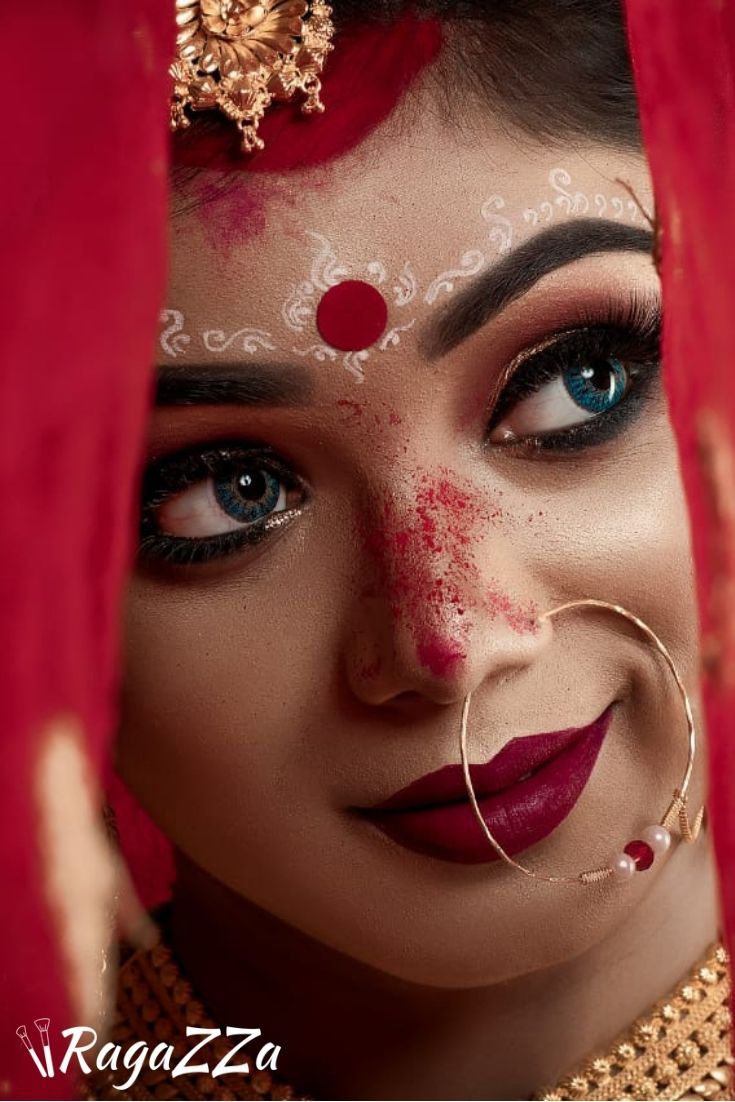 a woman with makeup on her face and red veil over her head, looking at the camera