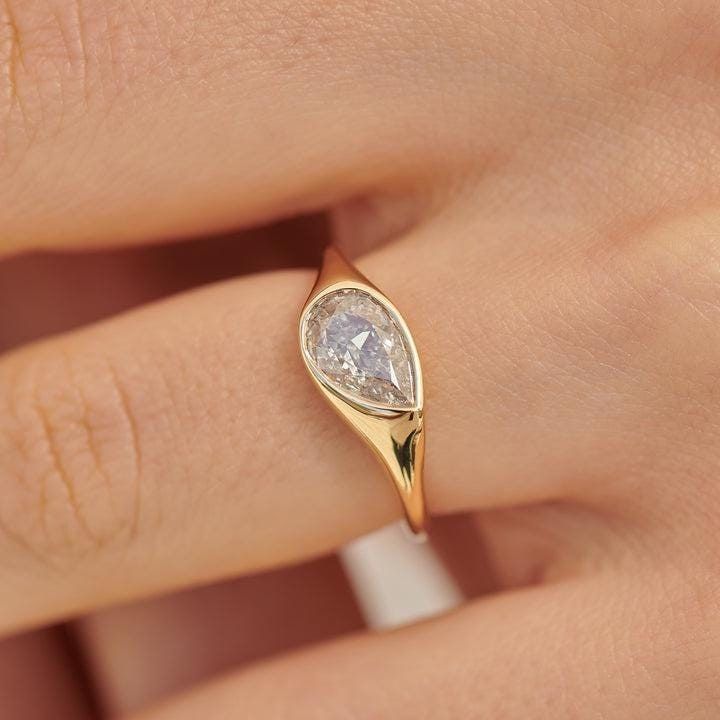 a woman's hand with a yellow gold ring on it and a white diamond in the middle