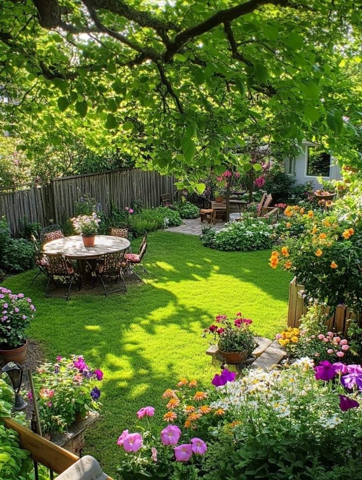 a garden with lots of flowers in the grass and tables surrounded by plants on either side