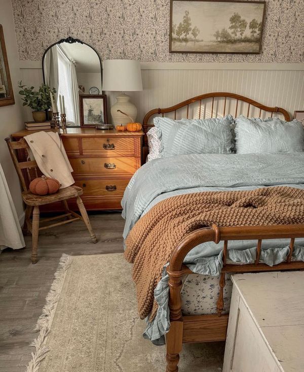 a bed sitting in a bedroom next to a wooden dresser and mirror on top of a rug